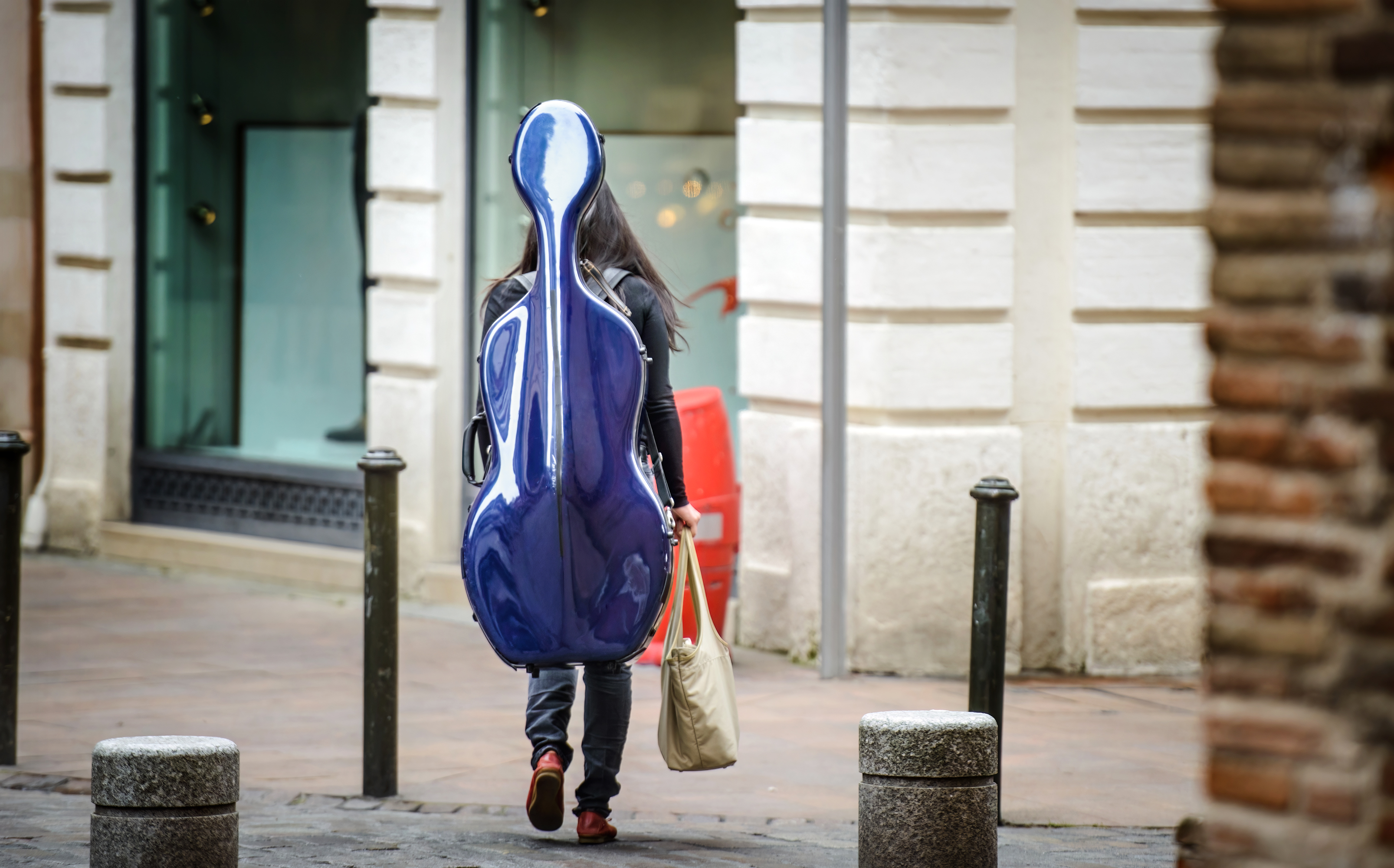 Cellistin mit blauem Cellokasten im Alltag